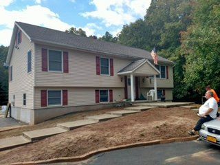 Beige vinyl siding with red shutters on a raised ranch