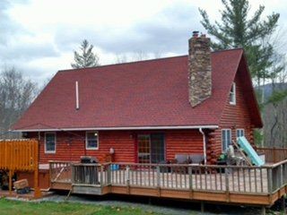 Log home with a new red roof and stone chimney
