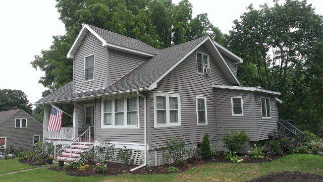 Corner view of a two-story home with new shingle roof and gray siding