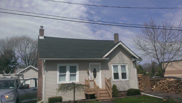 Small bungalow with a new dark shingle roof under a winter sky