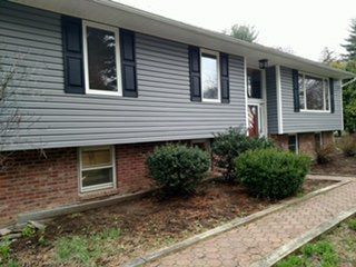 Gray vinyl siding with navy shutters over a brick base